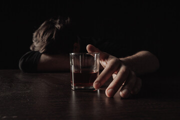 Male alcoholic with glass of whiskey lying or sleeping on table at night. Alcohol addiction concept