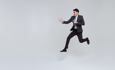 Fototapeta na wymiar handsome happy energetic young Asian businessman jumping in mid-air and hand pointing isolated on white copy space background.
