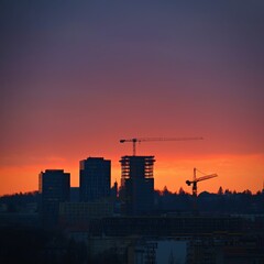 Fototapeta na wymiar Construction of buildings with a crane, workers and construction machinery at sunset. Concept for construction and industry.