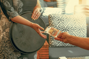 Hand of the waitress takes 50 euro tip. The waiter girl receives a tip from the client at the hotel...
