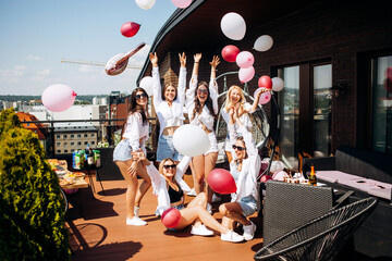 Happy and cheerful group of women friends together dancing and having fun on the rooftop at home. Bachelorette party.