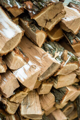 The wood is stacked on top of each other. A log pile. Heating season. Kindling for the stove. Wood for a cozy fire. Logs in large quantities. 