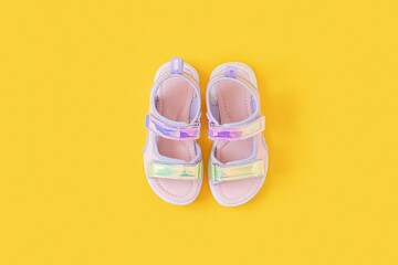 Stylish holographic sandals for kids on yellow background. Shiny fashion summer shoes. Flat lay, Top view