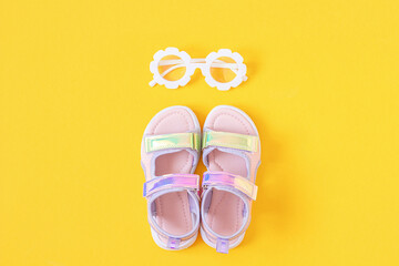 Stylish holographic sandals for kids on yellow background. Shiny fashion summer shoes. Flat lay,...