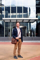 smiling business man in front of office building entrance, concept of work and lifestyle, copy space for text