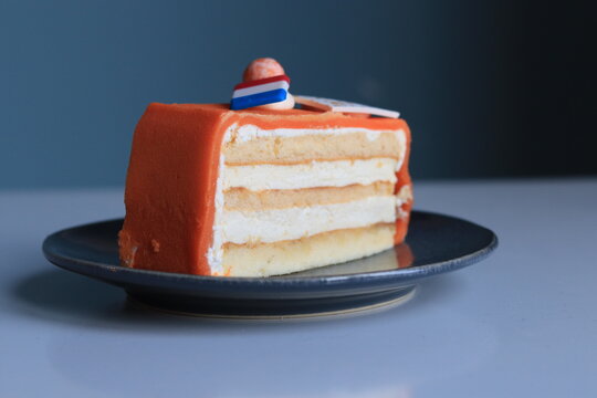 Orange Chipolata Pie Slice, Cake. With Red White Blue Little Flag On Top