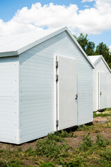 Naklejka premium Chicken coops stand in an open area. Around the nature: forests and fields. Organic farming. Life in the countryside. Raising chickens and geese.