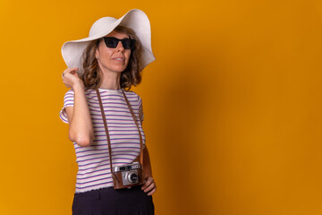 Caucasian girl in tourist concept with a hat and sunglasses enjoying summer vacation, yellow background