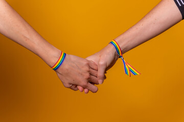 Hands of two women, LGBT concept on a yellow background, lesbian girl couple