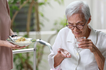 Asian senior patient taking medication,drugs pills and capsules before meal,treatment of...