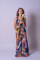 Portrait of a blonde Caucasian woman in a vintage floral dress with a flower in her hand on white background