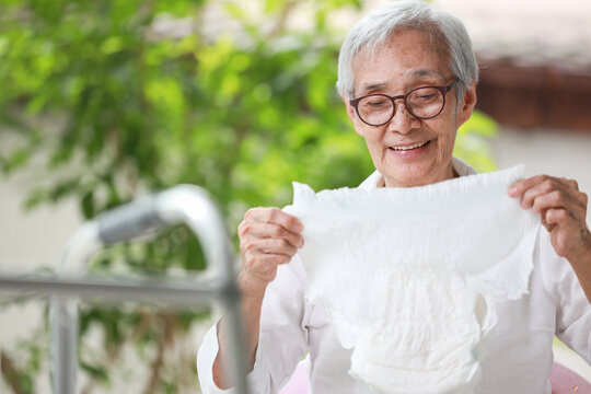 Happy Smiling Asian Senior Woman Holding Disposable Diaper For Adult,looking At Nappy Pamper With Satisfaction,old Elderly Patient With Urinary Incontinence,consumer Goods,health Care Concept