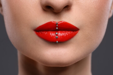 Obraz premium Young woman with red lips makeup on grey background, closeup