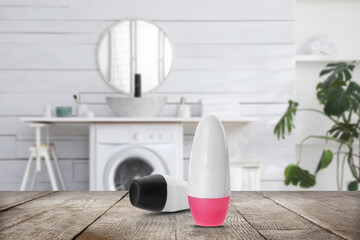 Different roll-on deodorants on wooden table in bathroom. Mockup for design