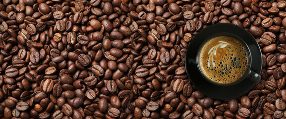 Cup of tasty aromatic coffee on roasted beans, top view. Banner design