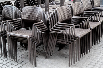 gray chairs of a street cafe are collected in one place