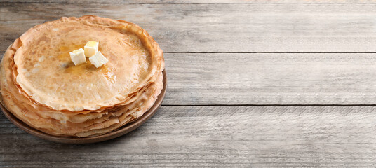 Stack of delicious crepes with melting butter on wooden table, space for text. Banner design