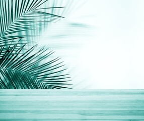 Fototapeta na wymiar Palm branches and light blue wooden table near white wall, space for text. Summer party