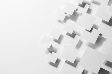 White abstract geometric background with fly rhombuses in bright light with soft gradient grey shadows, as border, copy space, top view. Simple mosaic backdrop in minimalist style.