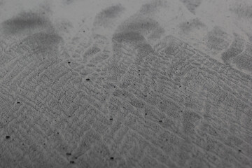 Black volcanic sand on beach with divorces, texture, background.