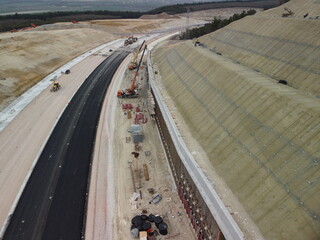 Workers reinforce the slope over the new road. Road construction in progress on slope nature...