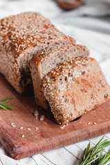 Sliced fresh bread with sesame seeds on a wooden board. Texture of a whole grain bread.