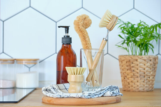 eco-friendly dishwashing brushes with organic bristles and wooden handle next to dishwashing detergent on the kitchen table. The concept of minimum consumption, zero-waist
