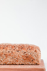 Fresh loaf of sesame bread on a wooden board on a white background. Side view. Copy space.