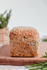 Freshly baked bread with sesame seeds and rosemary on a wooden board. Healthy baked bread. Copy space.