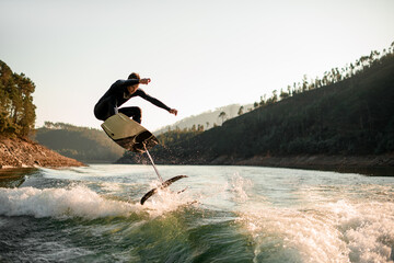 young active man jump with foil wakeboard over splashing wave