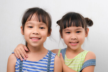 Two little sisters hugging and looking at camera isolated on white background. Two pretty little girls sisters happily cuddle and laugh. friendship and love concept.