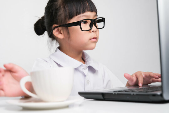 Little businesswoman with laptop working in office with coffee cup on table. children and business concept. - Powered by Adobe