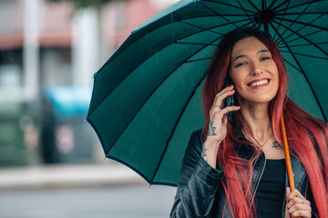 girl on the street with umbrella and mobile phone