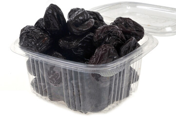 Barquette en plastique de pruneaux en gros plan sur fond blanc