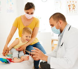 Fototapeta premium child doctor hospital patient medical nurse medicine health woman boy care mask protective epidemic corona virus healthcare pediatrician stethoscope clinic toy man mother