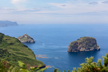 Picturesque emerald Basque coast along Bay of Biscay with rocky islands on shelf and piercing blue water of Bay of Biscay. Cabo Matxitxako, Biscay, Basque Country, Spain