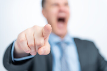Businessman in a dark jacket points at you with his finger and shouts loudly, shallow depth of...