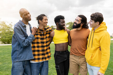 group of diverse gay men hugging each other in city park - transgender man in makeup, multiracial group