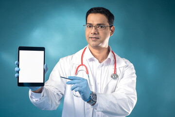 Treatment recommendation. Man doctor with tablet. Owner of private clinic demonstrates tablet. Tablet computer mock up. Advertising private hospital concept. Indian guy doctor. Copy Space on white