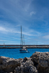Obraz premium Sailing yacht view behind rocks in day light.
