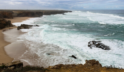 High angle view of the bay with sand beach and waves crashing - rough sea in Portugal