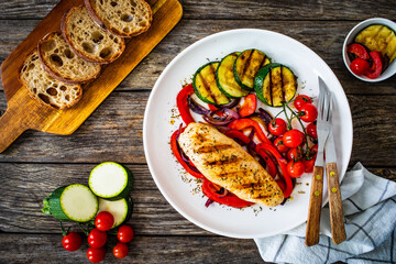 Grilled chicken breast with pepper, zucchini and cherry tomatoes on wooden table

