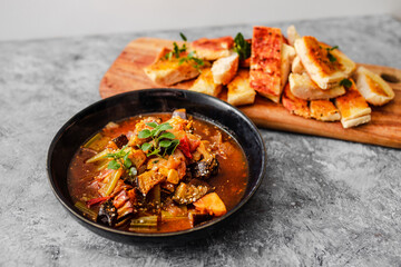 healthy plant-based food, vegan turkish güveç hot pot with eggplant celeri and potaotes in spicy broth with garlic bread