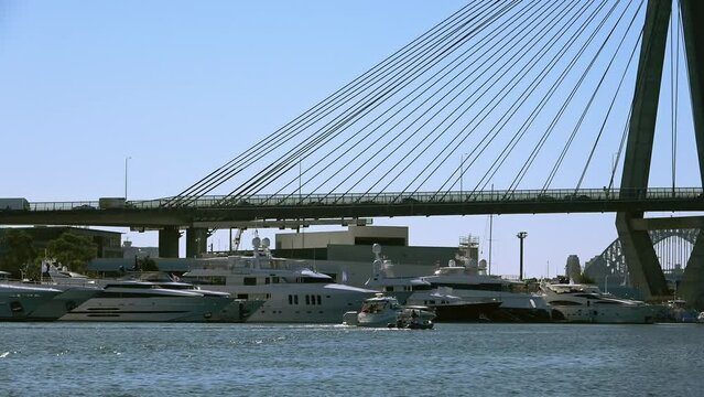 Sydney ANZAC Bridge, seeing boats driving under the bridge along the river and seeing cars traffic on the bridge in NSW Australia