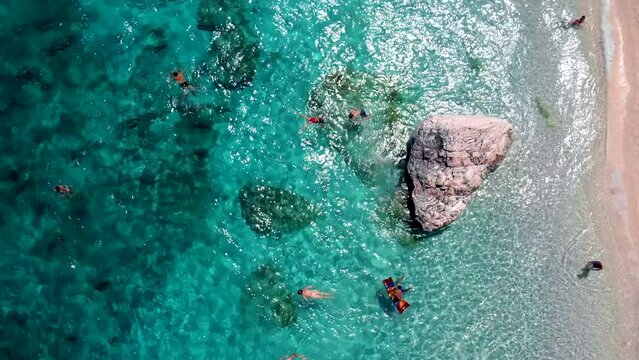 Golfo di Orosei Sardina, View from above, stunning aerial view of a beach full of beach umbrellas and people sunbathing and swimming on turquoise water. Cala Gonone, Sardinia, Italy, Cala Mariolu.