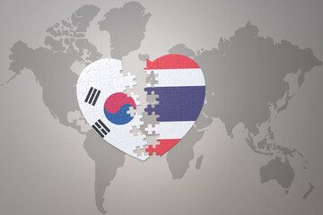 puzzle heart with the national flag of thailand and south korea on a world map background. Concept.