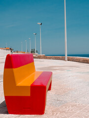 Bench in Spanish colors on the promenade overlooking the sea. The inscription on the promenade "I love Calpe"