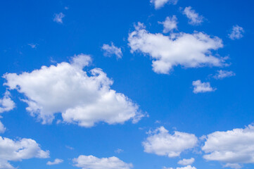 Blue sky summer background with white fluffy clouds.