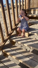 una niña en la playa tomando un refresco 