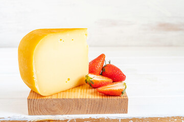 Smoked Gouda cheese and fresh strawberries on wooden background with copy space.